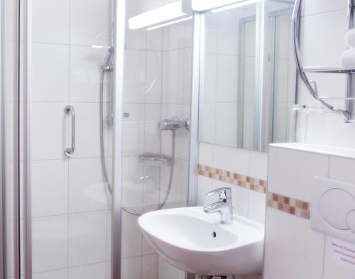 a white bathroom with a sink and a shower at Chalet Swiss - Appartementhotel in Bad F&uuml;ssing