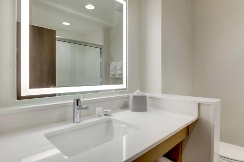 a white bathroom with a sink and a mirror at Holiday Inn Express Holly Springs - Raleigh Area by IHG in Holly Springs