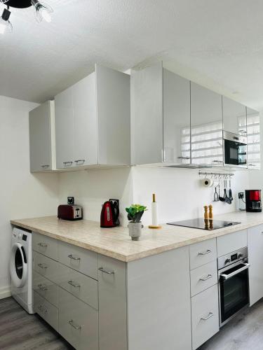 a kitchen with white cabinets and a counter top at SAB Location - Appartement in Ducos