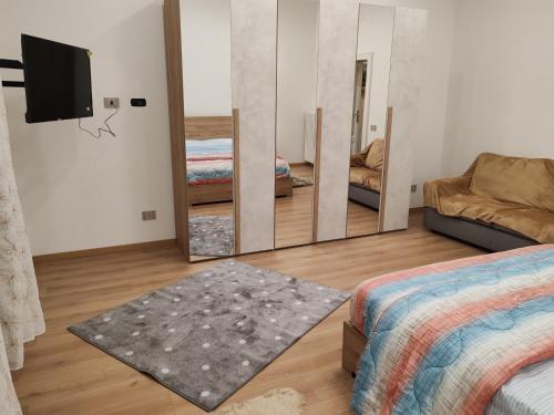 ein Schlafzimmer mit einem Spiegel, einem Bett und einem Sofa in der Unterkunft Appartamenti Lungo Fiume 506 in Sesto Calende