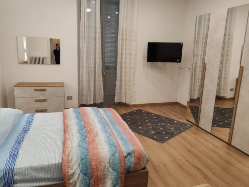 ein Schlafzimmer mit einem Bett und einem Spiegel sowie einem TV in der Unterkunft Appartamenti Lungo Fiume 506 in Sesto Calende