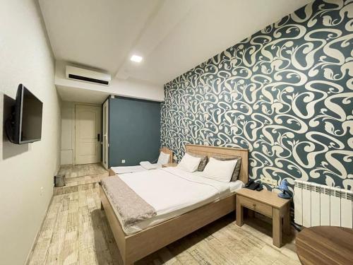 Nizami Street Hotel في باكو: غرفة نوم بسرير وجدار جداري