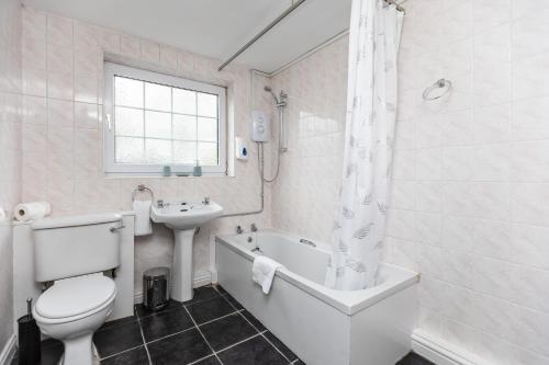 a bathroom with a toilet and a tub and a sink at Spacious three bedroom property! in Hemsworth