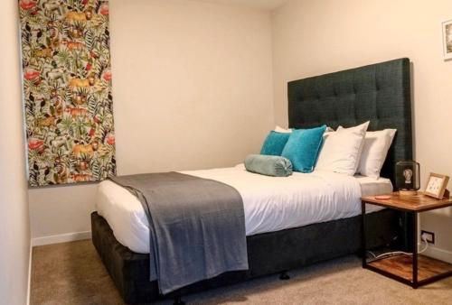 a bedroom with a large bed with blue pillows at Kārearea Lakehouse at Lake Pukaki in Lake Pukaki