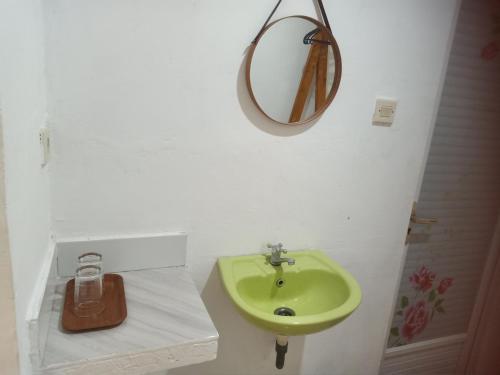 a bathroom with a green sink and a mirror at Renata Cottage in Langgur