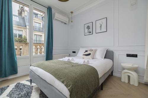 a white bedroom with a bed and a window at Poetic Stay - Champs Elysees in Paris