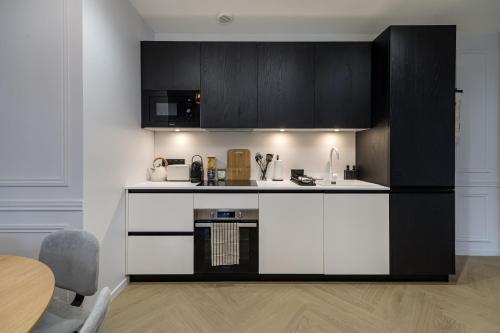 a kitchen with white and black cabinets and a table at Poetic Stay - Champs Elysees in Paris