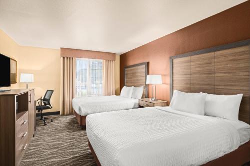 HamiltonにあるBitterroot River Inn and Conference Centerのベッド2台とテレビが備わるホテルルームです。