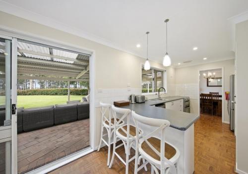 a kitchen and living room with a counter and stools at Hillcrest House - Gem in the Hunter! in Pokolbin