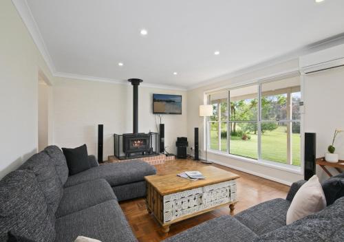 a living room with a couch and a fireplace at Hillcrest House - Gem in the Hunter! in Pokolbin