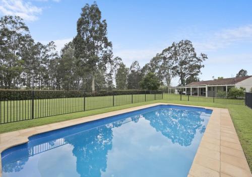 a swimming pool in a yard with a fence at Hillcrest House - Gem in the Hunter! in Pokolbin