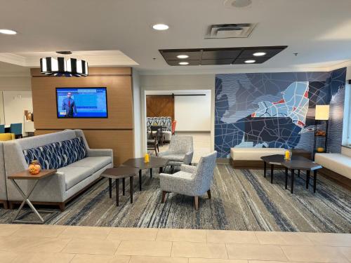 a lobby with a couch and chairs and a tv at Holiday Inn Express & Suites Dewitt - Syracuse by IHG in East Syracuse