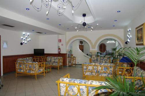 a waiting room with chairs and tables and a tv at Hotel Villa Belvedere in Cefalù