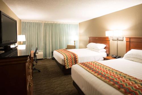 a hotel room with two beds and a flat screen tv at Pear Tree Inn Cape Girardeau Medical Center in Cape Girardeau