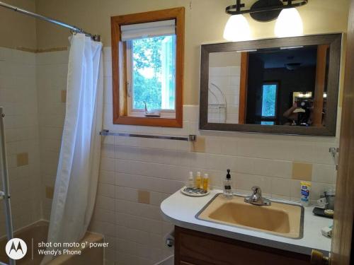 a bathroom with a sink and a mirror and a shower at Bass Creek's Cozy Outback Country Retreat in Janesville