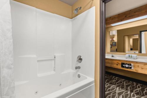 a bathroom with a tub and a sink and a mirror at Bitterroot River Inn and Conference Center in Hamilton