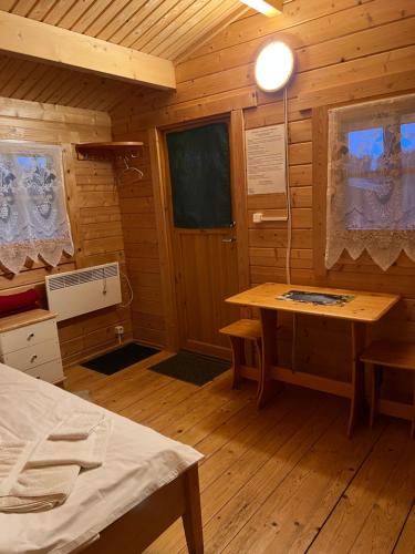 una habitación con una cama y una mesa en una cabaña en Artur´s Eaterie and Holiday home, en Viitna