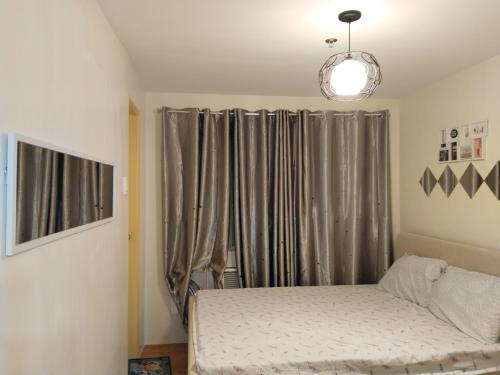 1 dormitorio con 1 cama y una ventana con cortinas en Seawind Condominiums Tower 1,3,4,5 en Dávao