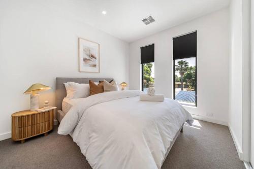 a white bedroom with a large bed and windows at Terra Haus - Renovated WiFi Glenelg in Glenelg