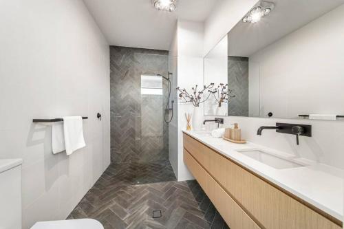 a white bathroom with a sink and a shower at Terra Haus - Renovated WiFi Glenelg in Glenelg
