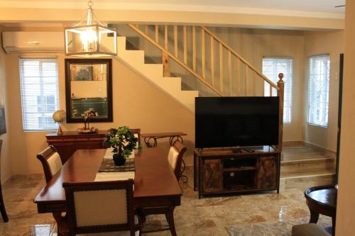 sala de estar con TV, mesa y escalera en Soleil Palm View Villa, en Priory