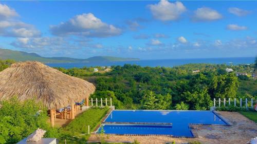 a resort with a swimming pool and a straw hut at Oasis en la naturaleza Rancho alto bonito in Las Galeras