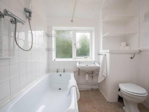 baño blanco con bañera, aseo y lavamanos en Large 4 Bed House near River Thames, en Old Windsor