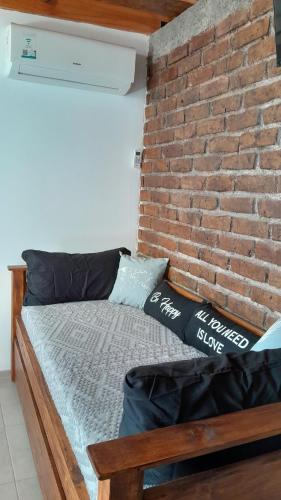 a bed in a room next to a brick wall at Hermoso Departamento En La Ciudad De Mendoza in Barraquero