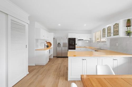 a white kitchen with white cabinets and a wooden floor at The Arches ~ Style, location and spacious living! in McLaren Vale