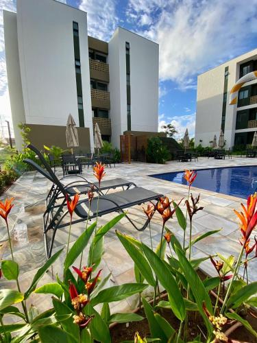a resort with a swimming pool and some flowers at Mana Beach Experience Muro Alto C219 in Porto De Galinhas
