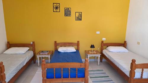 two twin beds in a room with yellow walls at Suíte Beach Host - Praia Pernambuco in Guarujá