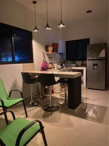 uma cozinha com uma mesa e cadeiras verdes em FINCA SAN SEBASTIAN em Tizimín
