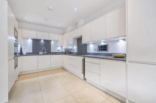 a large white kitchen with white cabinets and appliances at Elegant 4-Bed Townhouse in Northampton - Free Parking in Northampton