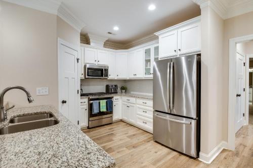 a kitchen with white cabinets and a stainless steel refrigerator at Charming Alabama Retreat with Private Patio! in Owens Cross Roads