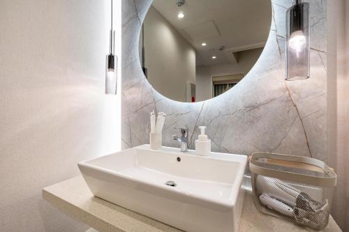 uma casa de banho com um lavatório branco e um espelho. em Hotel STAY ARI Higashishinjuku em Tóquio