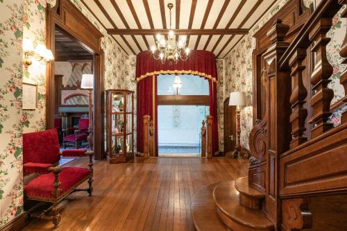 uma sala de estar com um lustre e uma cadeira vermelha em Grand Hôtel Des Templiers em Reims