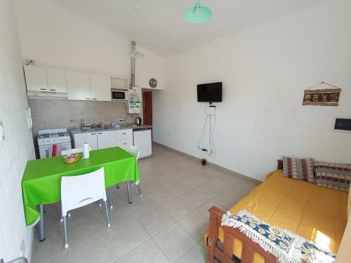 een woonkamer met een groene tafel en een keuken bij Departamentos Universidad in Río Cuarto