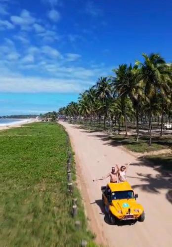 two people riding on top of a yellow car on a beach at Mana Beach Experience Muro Alto C219 in Porto De Galinhas