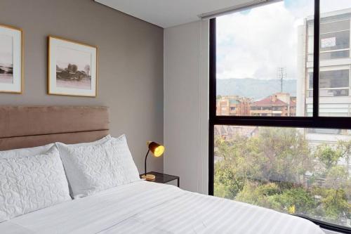 een slaapkamer met een wit bed en een groot raam bij Unicentro North Retreat 2 Rooms in Bogota