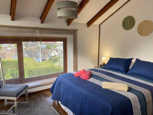 Un dormitorio con una cama azul con una silla y una ventana en Felices Sueños, Entre Volcanes ., en Puerto Varas