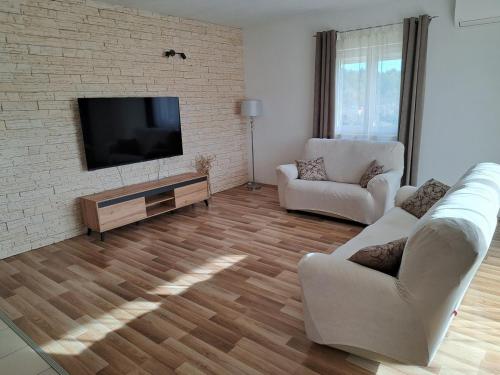 ein Wohnzimmer mit 2 Stühlen und einem Flachbild-TV in der Unterkunft Family friendly house with a swimming pool Sibenik - 21939 in Šibenik