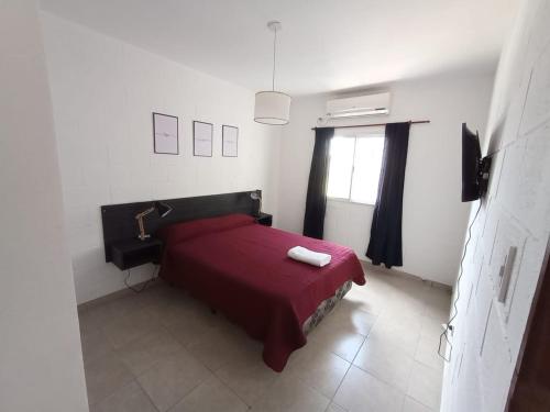 a bedroom with a red bed and a window at Departamentos Universidad in Río Cuarto