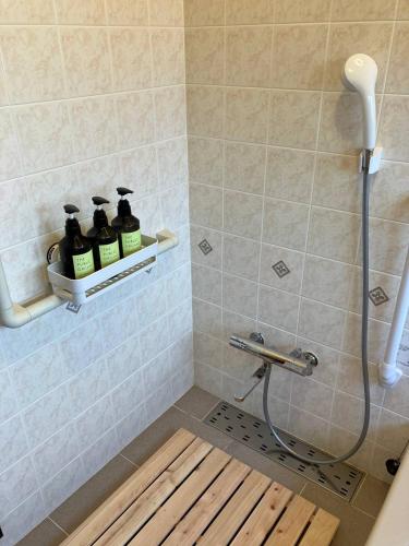 a bathroom with a shower with three bottles of soap at 貸し別荘 Key of Private Villa 'ムササビハウス' in Kita-karuizawa