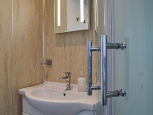 ein Bad mit einem Waschbecken und einem Spiegel in der Unterkunft Swallow Lodge in Carsphairn
