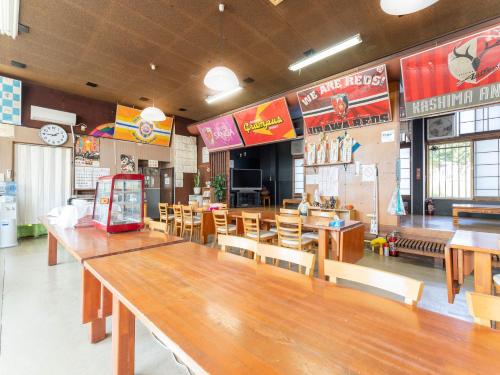 a restaurant with a large wooden table and chairs at Minshuku Hirono in Ōyauchi