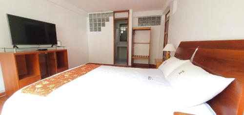 um quarto com uma cama e uma televisão de ecrã plano em Hotel Romero Machupicchu em Machu Picchu