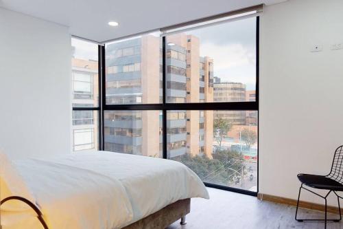 a bedroom with a white bed and a large window at Unicentro Delight Norte Bogotá 2 habitaciones in Bogotá