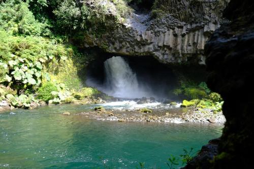 a waterfall in a cave next to a river at Cabaña Bosque Río in Pucón