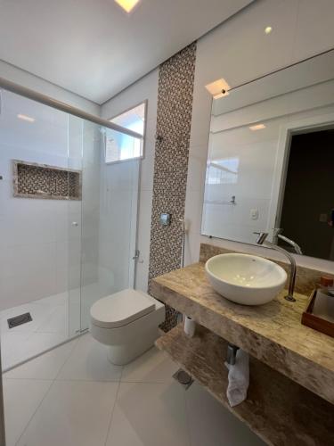 a bathroom with a sink and a toilet and a mirror at Apto beira mar pé na areia in Caraguatatuba