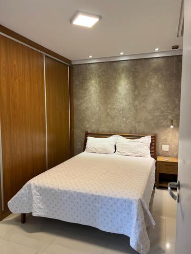 a bedroom with a large bed with white sheets at Apto beira mar pé na areia in Caraguatatuba